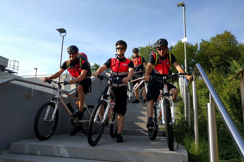 Vier Männer in Signalwesten auf Fahrrädern auf einer Betontreppe.