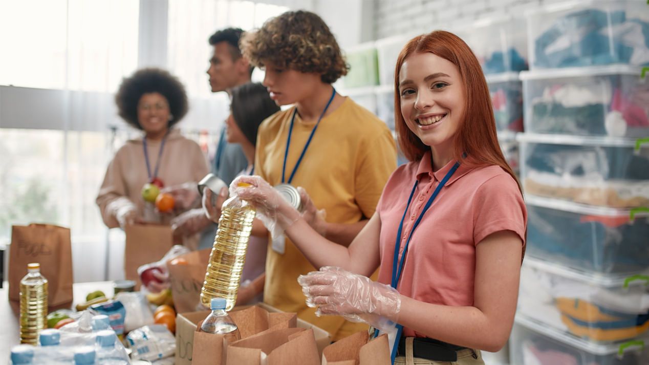 Eine Gruppe junger Menschen packt Lebensmittelspenden in Kartons ein