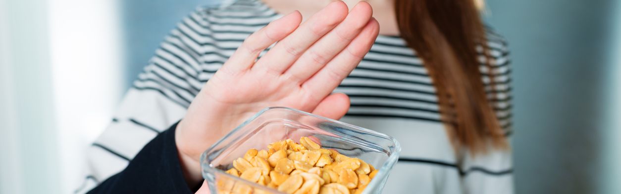 Junge Frau lehnt eine Schale mit Nüssen mit ihrer Hand ab