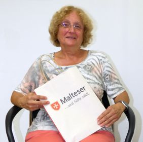 Evlira Viemann hält eine Tasche mit Malteser Logo