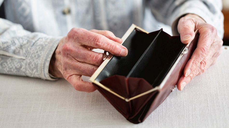 Hände einer älteren Frau öffnen ein Portemonnaie.