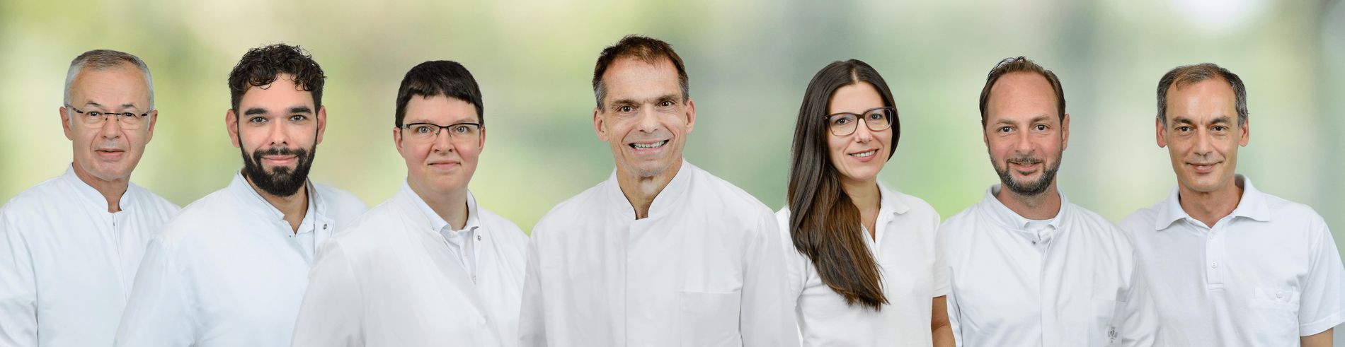Sieben medizinische Fachkräfte der Klinik für Kardiologie und Angiologie in weißen Kitteln stehen nebeneinander.