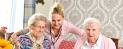 Eine Pflegekraft mit zwei Seniorinnen. 