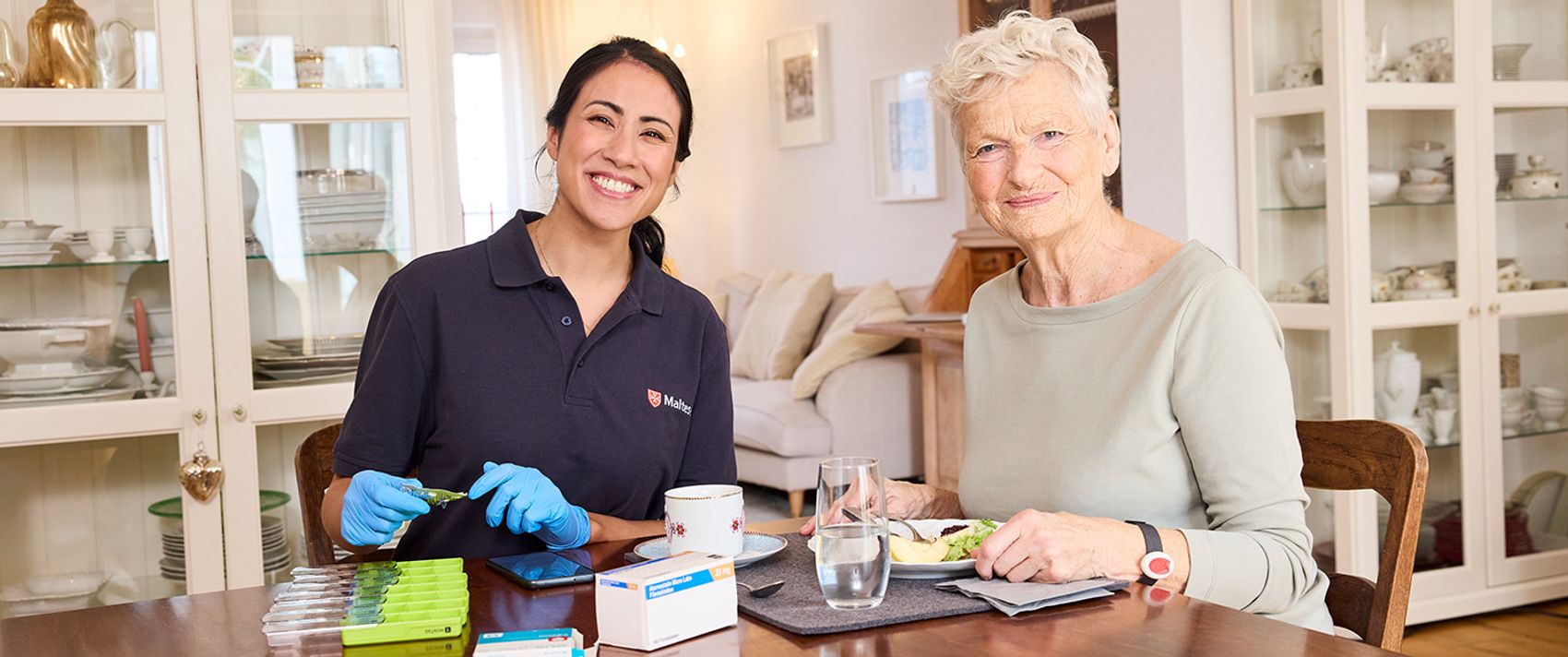Mitarbeiterin des ambulanten Pflegedienstes gibt Patientin Medikamente.