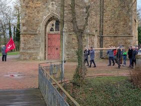 Vier Männer tragen das schwere Holzkreuz am Anfang der Prozession um die Kirche