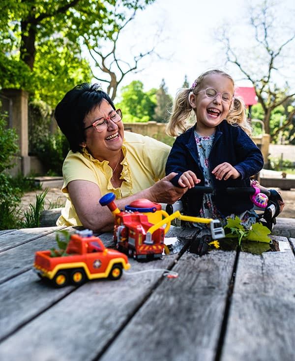 Kleines Mädchen und Frau spielen auf dem Spielplatz und lachen.