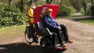 Eine Helferin der Lohner Malteser fährt einen älteren Herren in einer Rikscha im Hopener Wald.