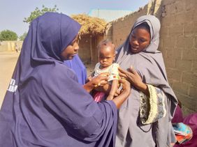 Zwei Frauen aus Nigeria halten einen Jungen