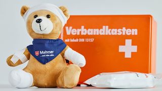 Erste Hilfe Verbandskasten mit Teddy, der verbunden und gepflastert ist