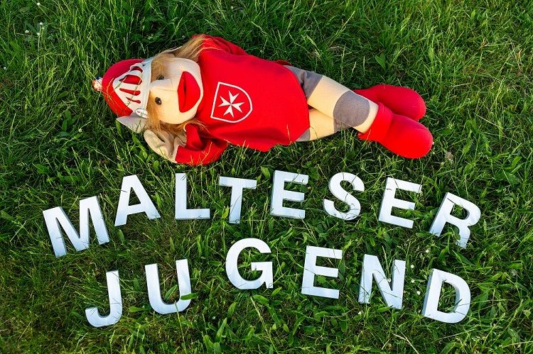 Schriftzug Malteser Jugend auf Gras und Maskottchen Ritter Malte