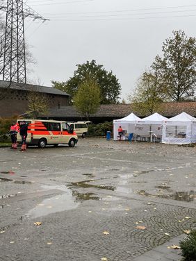 Pavillons und ein Einsatzfahrzeug der Malteser Gelsenkirchen stehen auf dem Vorplatz eines Friedhofs 