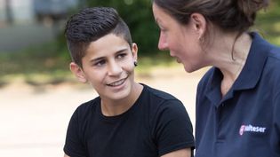 Eine junge Malteser Integrationslotsin unterhält sich mit einem Jungen.