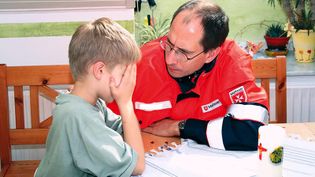 Ein Notfallseelsorger der Malteser spricht mit einem kleinen Jungen.