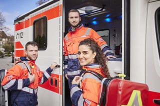 Einsatzkräfte des Rettungsdienstes vor einem offenen Rettungswagen