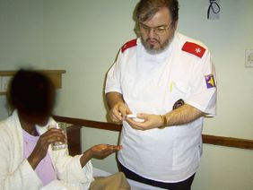 A staff member gives medication to a seated patient.