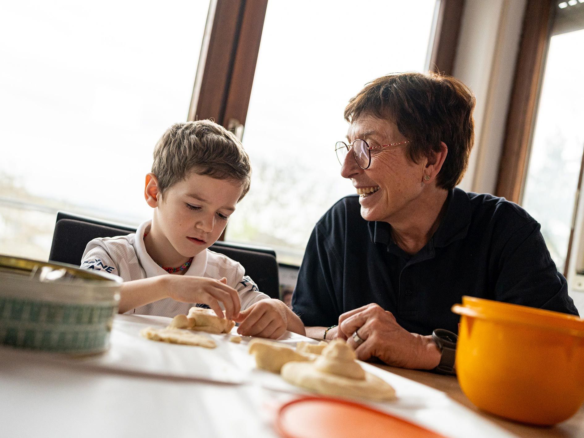 Eine Frau und ein Junge sitzen an einem Tisch und backen Gebäck
