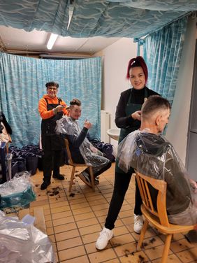 Friseurinnen schneiden zwei Gästen die Haare