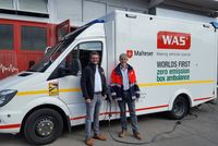 Joachim Fässler (r.), Malteser Geschäftsführer Rettungsdienst Bezirk Stuttgart, und Christoph Stegemann (WAS GmbH), zeigen den weltweit ersten Rettungswagen mit komplett elektrischem Antrieb im Malteser Rettungsdienst Stuttgart. Foto: Malteser 