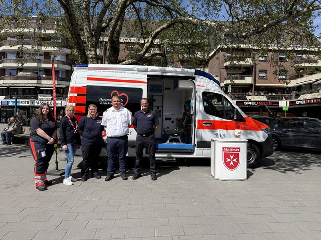 die beiden Stadtbeauftragten und drei ehrenamtliche Helfer stehen vor dem Herzenswunsch-Krankenwagen auf dem Spiel- und Sportwochenende in Oberhausen Strekrade