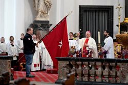 Ein Malteser trägt eine Fahne mit Malteser Kreuz