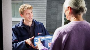 Malteser Mitarbeiter liefert eine Mahlzeit an eine Kundin. Essen auf Rädern.