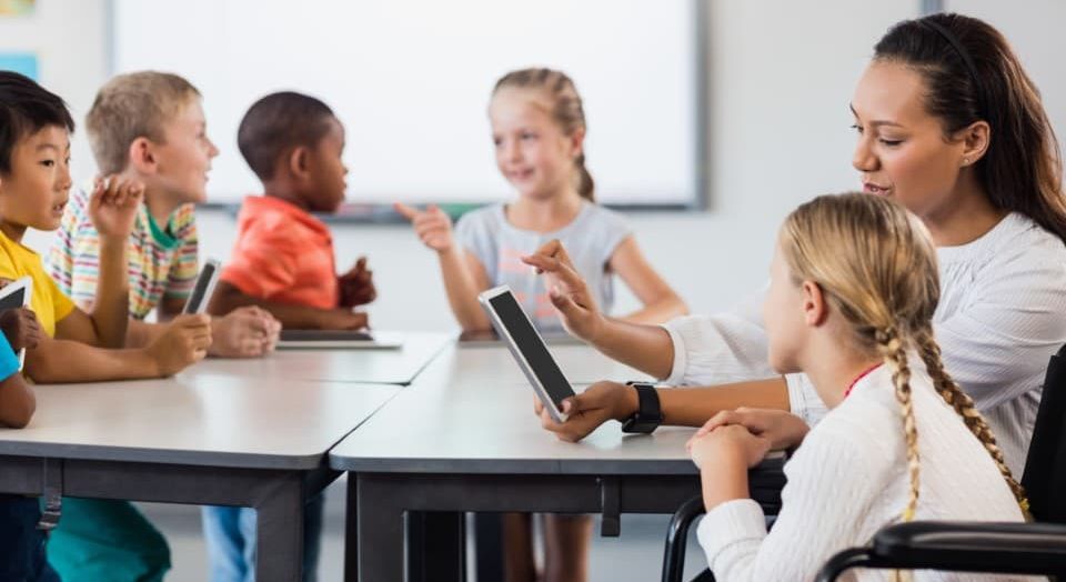 Schulbegleiterin mit einem Kind am Tablet