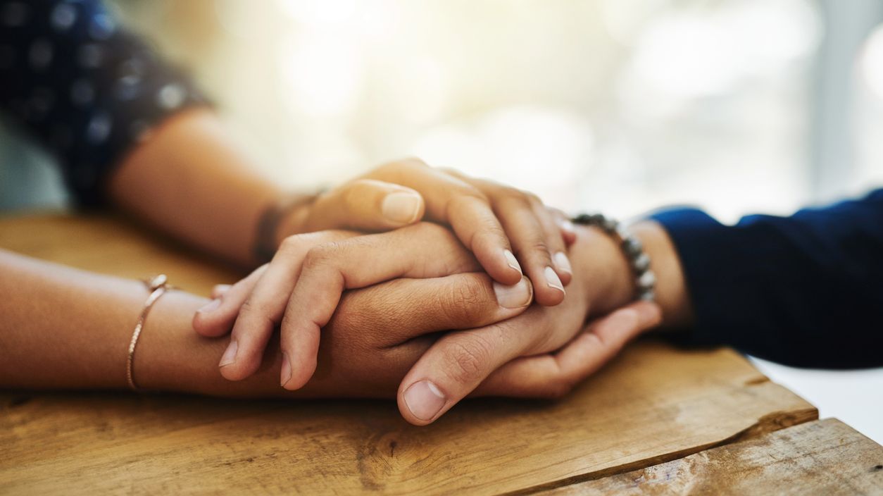 Die Hand eines jungen Mannes in den Händen einer jungen Frau.