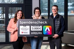 Drei Personen stehen in einem modernen Innenraum und halten gemeinsam einen großen Spendenscheck. Auf dem Scheck steht eine Spendensumme von 3.000 Euro zugunsten des „Malteser Kinder- und Jugendhospizdienstes Ostthüringen“. Logos der Malteser, von Barclays sowie von „ad hoc“ sind ebenfalls zu sehen. Im Hintergrund fällt Tageslicht durch große Fenster.