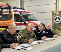 Vertreter der Bundeswehr, von Johannitern und Maltesern beim Unterzeichnen eines Vertrags
