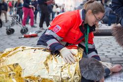 Foto © Malteser/Tim Tegetmeyer: Zum Wärmeerhalt wird die goldene Seite der Rettungsdecke nach außen um den Verunfallten gelegt.