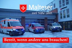 Drei Malteser Einsatzfahrzeuge mit Blaulicht vor Fahrzeughalle 