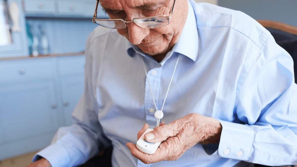 Ein älterer Mann mit Brille betätigt den Knopf eines Hausnotrufs.