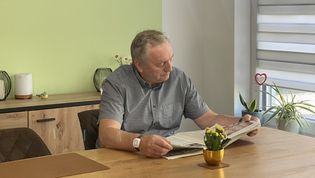 Ein Senior mit einem Hausnotruf-Armband beim Zeitunglesen