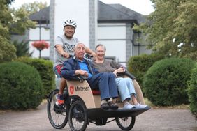 Rikscha-Pilot Uwe Klein mit Fahrgästen vor der Pfarrkirche St. Aegidius. 