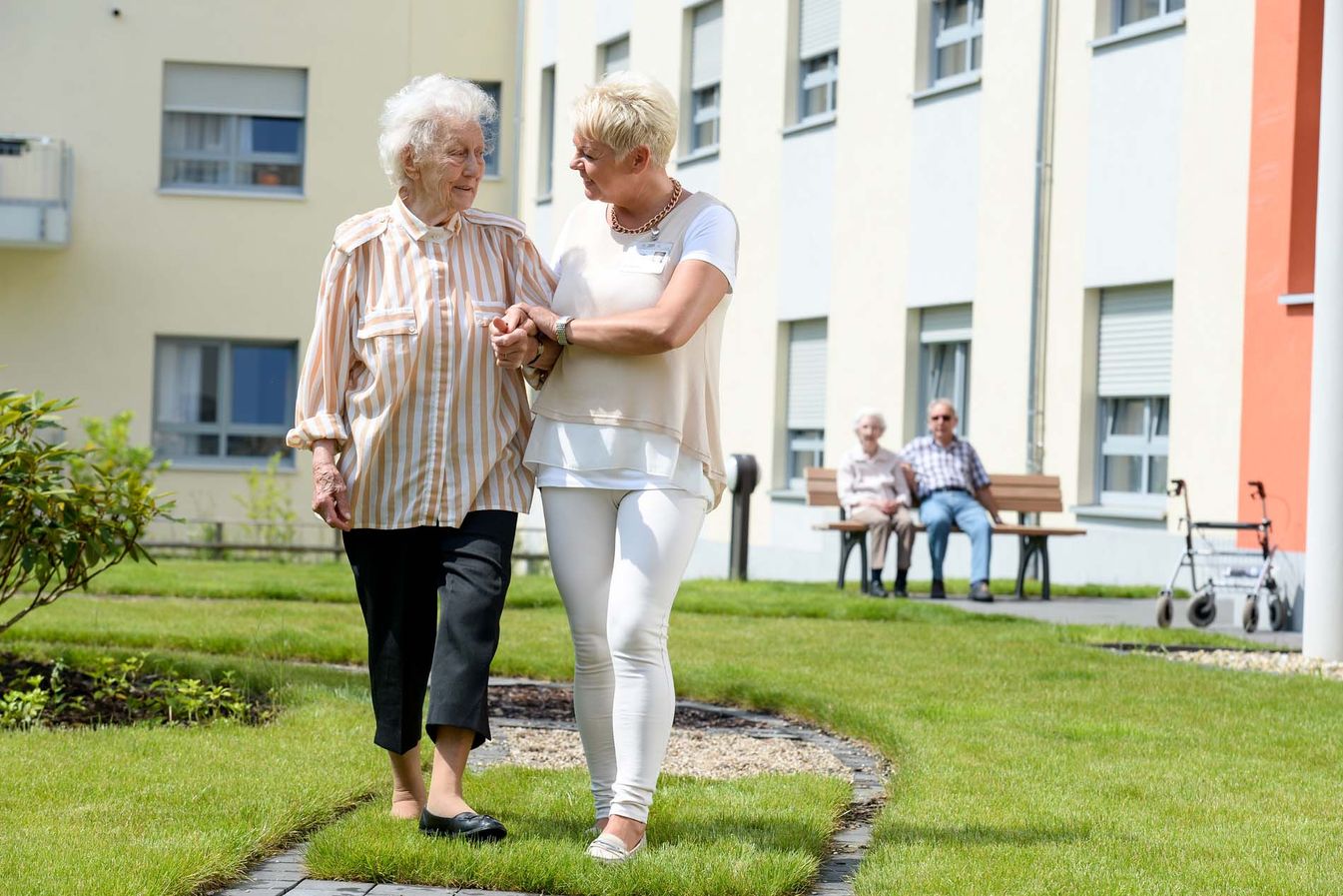 Pflegerin und Bewohnerin machen einen Spaziergang 