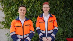 Zwei Männer in Dienstbekleidung des Rettungsdienst blicken freundlich in die Kamera.