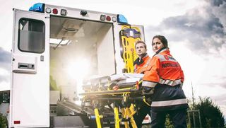 Malteser Rettungsdienstmitarbeitende verladen Krankenliege in Rettungswagen.