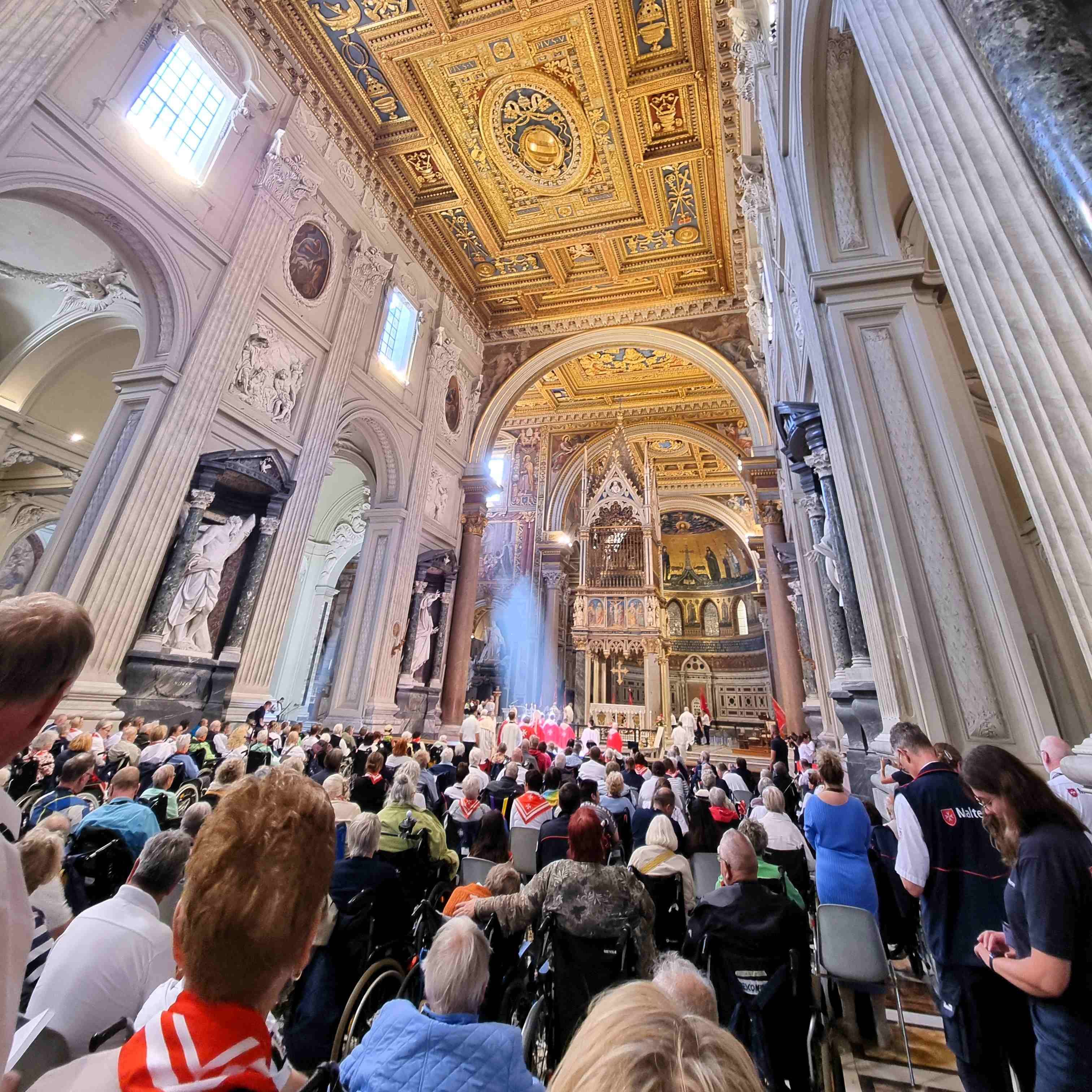 Innenraum des Lateran mit hoher Decke, Säulen und vielen Menschen bei einem Gottesdienst.