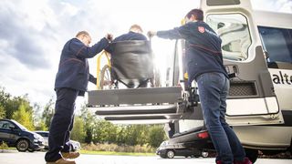 Zwei Mitarbeitende des Malteser Fahrdienstes helfen einer Person im Rollstuhl.