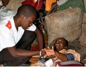 Care worker visiting Xolani at home and checking his blood pressure.