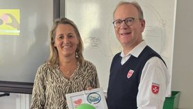 Eine Frau und ein Mann in Malteser Dienstbekleidung mit einer Urkunde