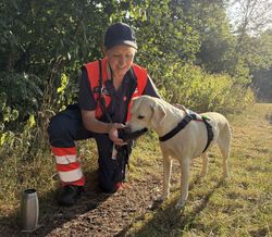 Eine Malteserin gibt einen Rettungshund zu trinken