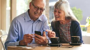 Ein älteres Paar sitzt in einem Café mit Smartphone.