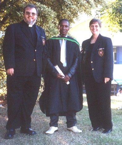 Peter Dunn in graduation gown between two members of the Brotherhood of Blessed Gérard.