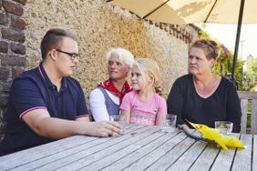 Ein Mitarbeiter der Malteser sitzt mit zwei Frauen und einem Mädchen an einem Tisch und spricht mit ihnen.