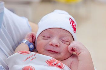 Neugeborenes Baby mit einer weißen Mütze