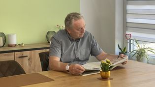 Ein Senior mit einem Hausnotruf-Armband beim Zeitunglesen