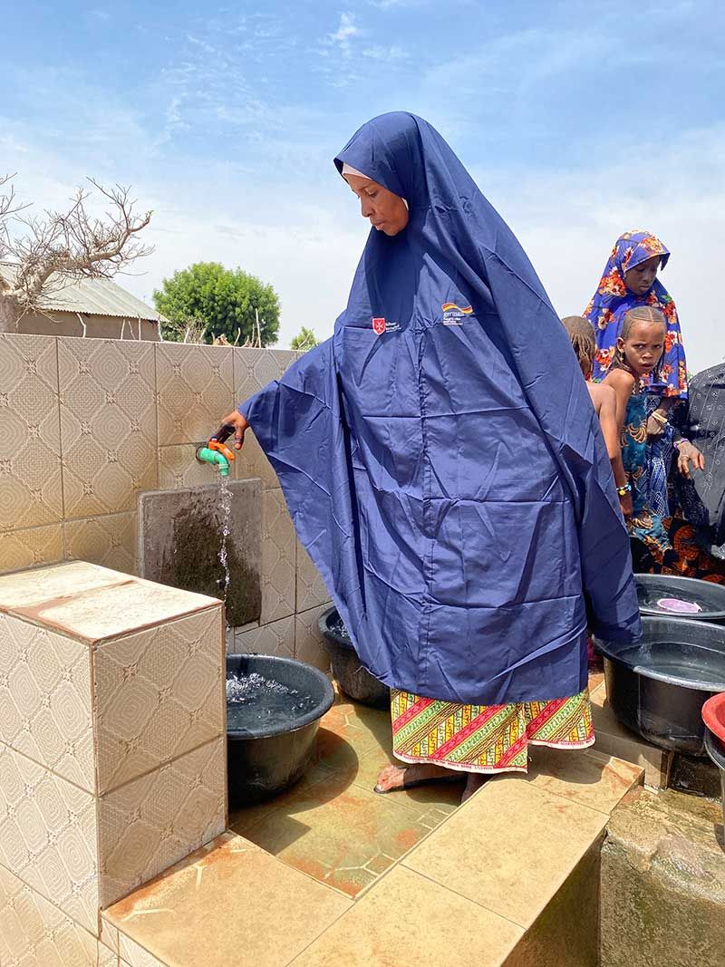 Eine Frau bedient vor einem Brunnen