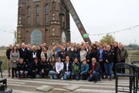 Alle anwesenden ehren- und hauptamtlichen Malteser versammeln sich zu einem Gruppenfoto auf der Terrasse, mit dem Förderturm im Hintergrund.