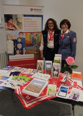 Zwei Frauen hinter Info-Tisch zu Malteser Hospizarbeit
